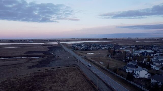 Car on road by neighbourhood community tilt aerial evening