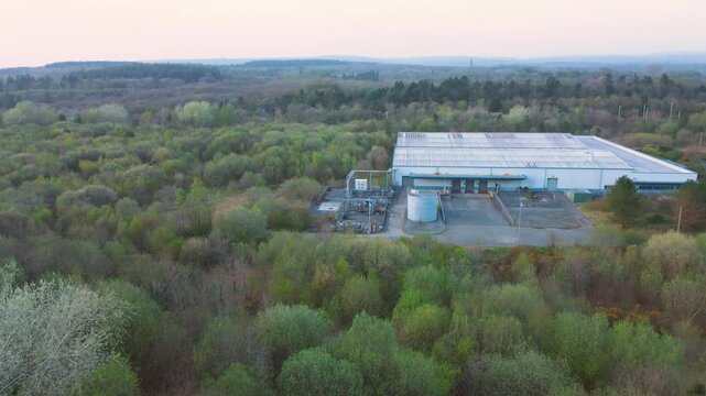 Drone Aerial View Over Warehouse with Loading Bays Surrounded by Forest Landscape. Industrial Infrastructre Surrounded by Natural Environment. 4K.