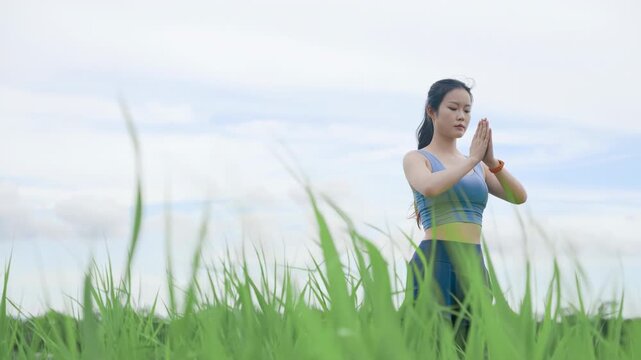 Young yoga teacher instructor practicing yoga lotus pose breathing meditation doing namaste gesture and keeping hands in mudra while stretching and shaping outdoor morning for losing weight