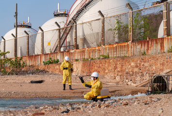 Workers test water quality by tanks at a coastal site during daylight © FotoArtist