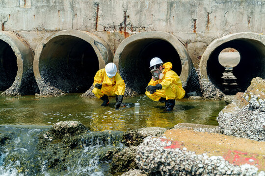 Workers conduct tests near water outlet in city during daytime for environmental assessment