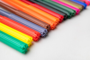 Fototapeta premium Close-up of bright rainbow-colored felt-tip pens on gray background. Felt-tip pens, markers for drawing, creative projects and crafts. School children's background. Selective focus