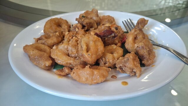 Cumi goreng telur asin. Crispy fried squid coated in creamy salted egg sauce, rich, savory, and slightly buttery. A popular Asian seafood dish with bold flavor and golden texture.