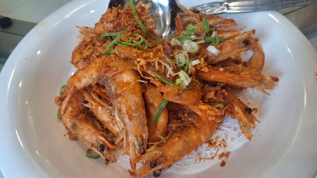 Udang goreng bawang putih.Golden fried shrimp infused with aromatic garlic, crispy on the outside and juicy inside. Simple yet flavorful seafood dish with appetizing texture and warm presentation.