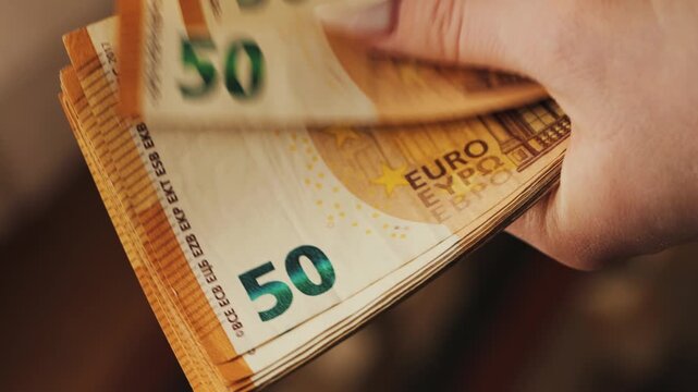 A woman counts a 50-euro note. Close-up of a hand counting a stack of bills. High quality 4k footage