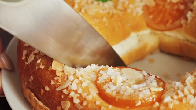 Roscon de reyes. A round cake baked from a rich yeast dough and decorated with sugar, almonds, and glazed fruit. Cutting a piece of cake with a knife. High quality 4k footage