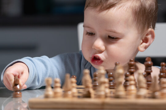 Cute toddler discovering chess, early training for brain development.