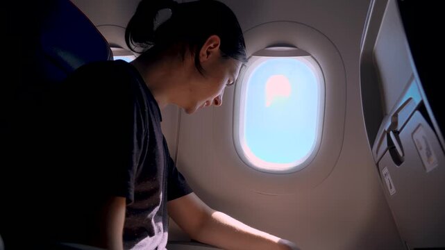 Nervous airplane passenger breathing deeply near cabin window during flight. Fear of flying panic moment with tense posture inside aircraft seat and bright sky outside. Aviation travel anxiety concept