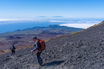 Fototapeta premium Tourists cross a lava field in Teide National Park.