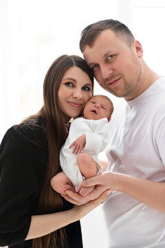 A loving family portrait featuring a newborn baby held gently by its parents, capturing a tender moment of new parenthood and connection