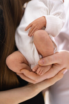 Close-up of tiny newborn baby feet and hands cradled in loving parents' hands, symbolizing new life and family connection