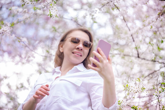 Happy woman in park looking at smartphone screen. Modern technology and digital communication.