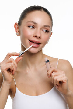 Young woman applies lipstick on lips. Beautiful young woman with clean fresh skin.