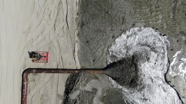 Top-down aerial view of industrial dredging pipe discharging sand slurry