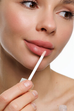 Young woman applies lipstick on lips. Beautiful young woman with clean fresh skin.