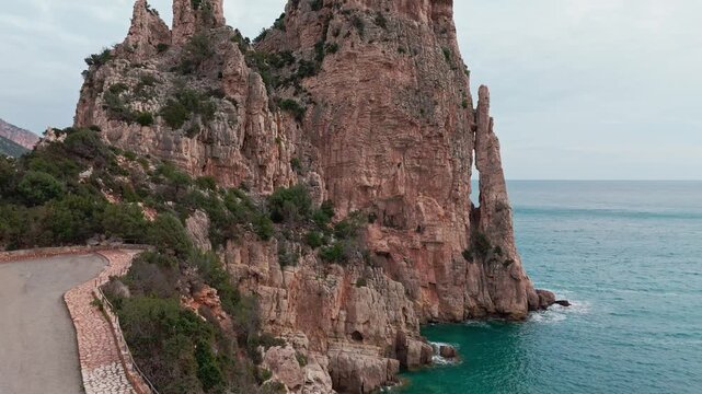 A stunning view of the iconic Pedra Longa limestone needle rising from the turquoise Mediterranean sea in Baunei, Sardinia.