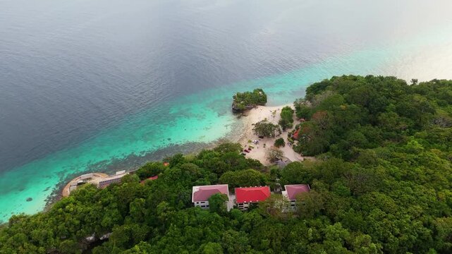 Drone shot of a remote tropical resort nestled in the dense green jungle of Siquijor Island. Isolated beach getaway with turquoise ocean views and authentic island architecture