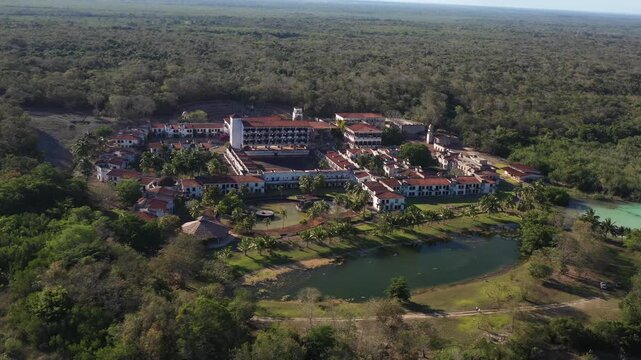 Drone aerial shot of the abandoned ghost hotel beside the Lagoon of Seven Colors in Bacalar, Mexico. Unique ruins surrounded by turquoise water, tropical nature, and iconic travel scenery.