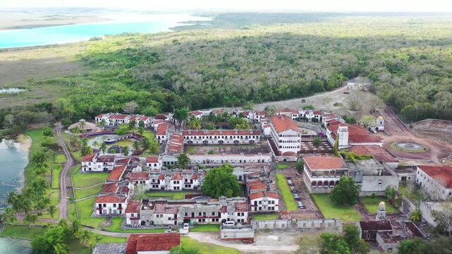 Drone aerial shot of the abandoned ghost hotel beside the Lagoon of Seven Colors in Bacalar, Mexico. Unique ruins surrounded by turquoise water, tropical nature, and iconic travel scenery.