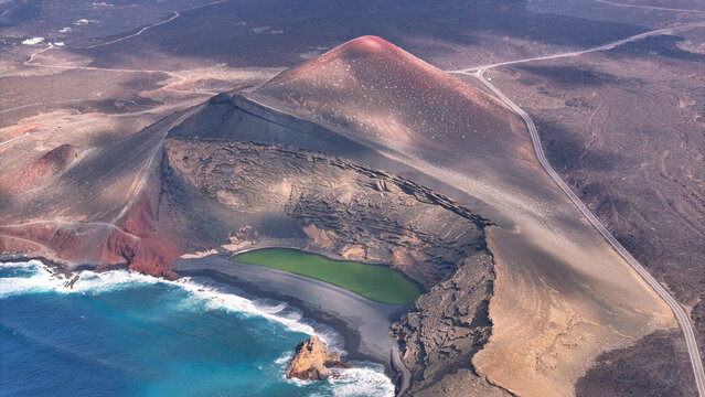 Aerial view of the Charco de los Clicos green lagoon nestled within a volcanic crater beside the Atlantic Ocean in El Golfo, Canarias, Spain.