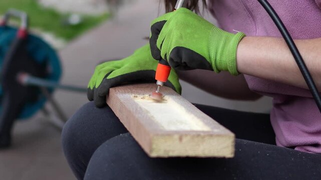 Working with an engraver. A woman cuts and processes wood; a woman creates handmade wood crafts using an engraver. Handcrafted woodwork in progress.
