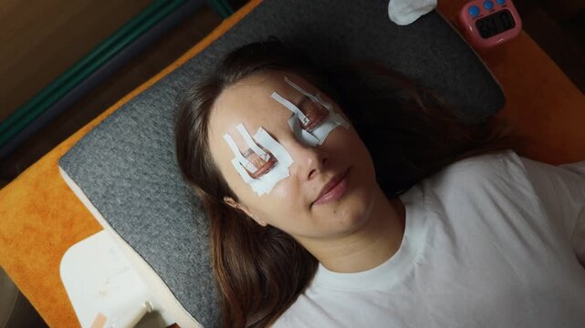 Woman receiving a lash lift, an eyelash perm procedure, with silicone rods and treatment solution protecting her lower lash line, enhancing her natural eye beauty at a professional salon or spa