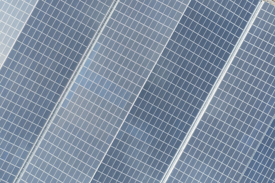 Aerial view of solar panels on the factory roof with blue grid patterns and reflective surfaces in Taiwan.