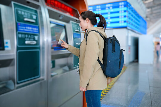 Woman Using Self-service Ticket Machine in Station