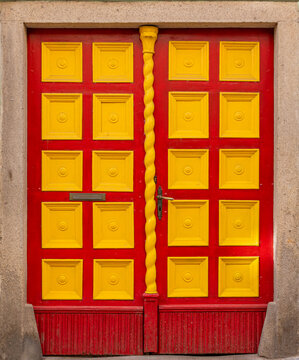 A colorful old red wooden door with yellow paneled sections