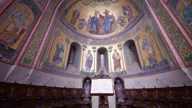 Modena, italy, april 11, 2026. Ornate golden mosaics depicting biblical scenes in the apse of the modena cathedral. Empty wooden choir stalls below the stunning artwork