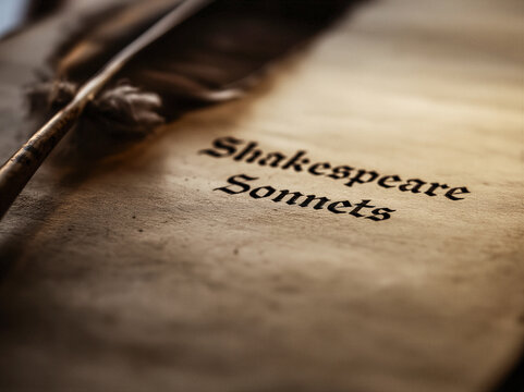 the words written in a quill Shakespeare Sonnets into parchment a a feather quill lays to the side, authentic shakspear scene