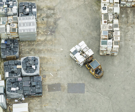 Aerial view of a forklift moving stacked appliances at a home appliance recycling plant with piles of refrigerators and televisions in Taiwan.