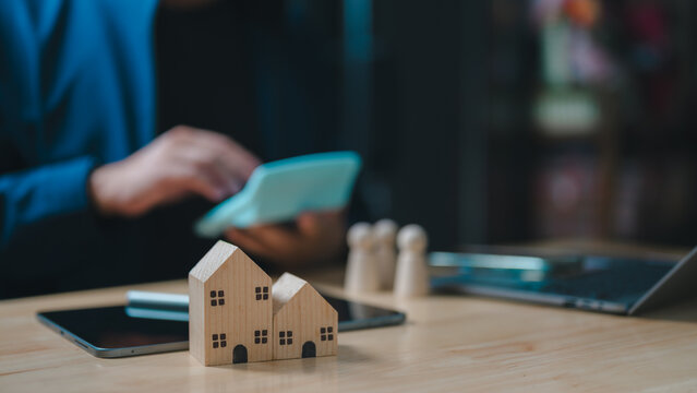 Professional businessman calculates mortgage costs utilizing wooden house models. Real estate investment planning involves financial analysis, property valuation, family housing goals, budget