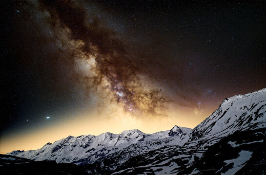 Beautiful night sky over mount Lukmanier in Switzerland in Spring. In the background, the light of big cities shines trough the night. 