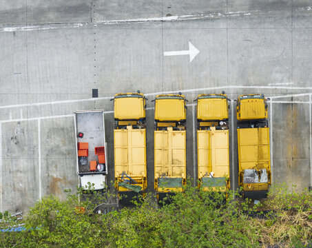 Aerial view of yellow garbage trucks and recycling vehicles parked in a row on a concrete lot with a white directional arrow Taiwan.