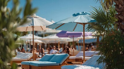 Obraz premium Group of lounge chairs and umbrellas on a sandy beach. the chairs are arranged in a row and are covered with blue cushions.