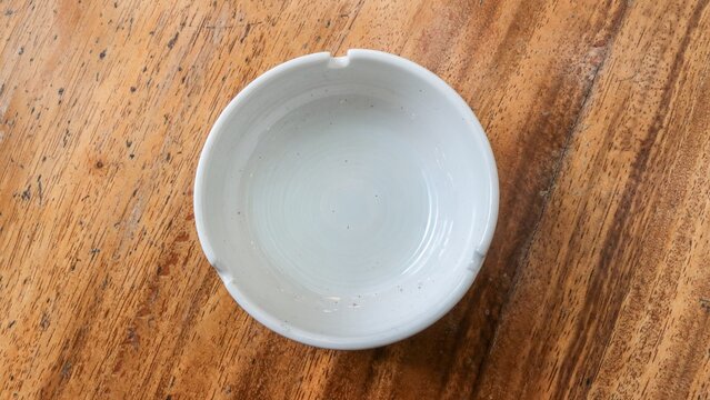Close up a white ashtray on wooden table