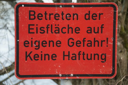 Sign "Betreten der Eisfl&auml;che auf eigene Gefahr! Keine Haftung", German for "frozen surface, enter at your own risk, no liability", black writing on red