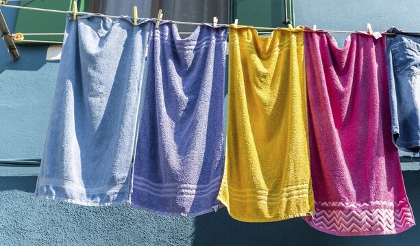 Colorful laundry on clothesline in front of blue house wall, Burano Island, Venice, Veneto, Italy