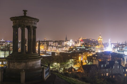 View from Calton Hill with the Dugald Stewart Monument over the historic Old Town with Edinburgh Castle at night, Edinburgh, Scotland, United Kingdom