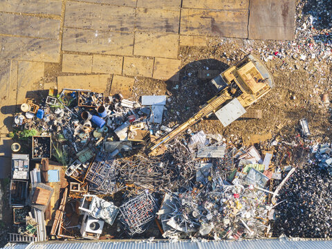Aerial view of a resource recovery plant with an excavator moving piles of scrap metal and industrial waste materials in Taiwan.