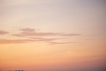 Obraz premium Warm golden sunset sky with soft, scattered clouds at twilight hour