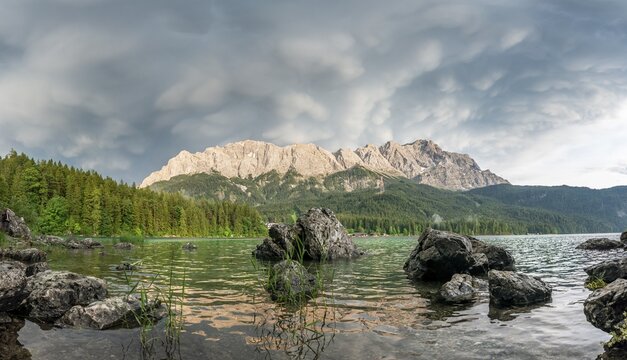 Rocks on the shore, Lake Eibsee lake in front of Zugspitze massif with Zugspitze, dramatic Mammaten clouds, Wetterstein range, near Grainau, Upper Bavaria, Bavaria, Germany