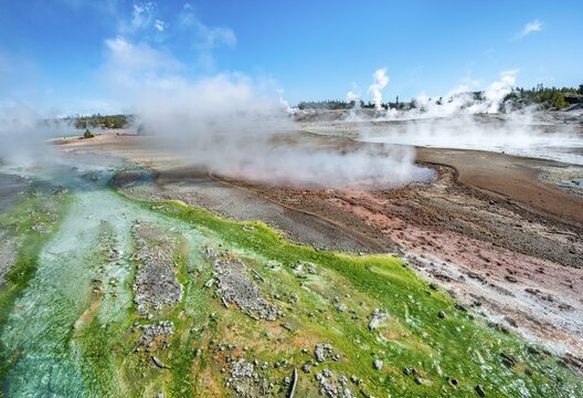 Red mineral deposits and green algae at a thermal spring, steaming hot springs, Whirligig Geyser, Noris Geyser Basin, Yellowstone National Park, Wyoming, USA