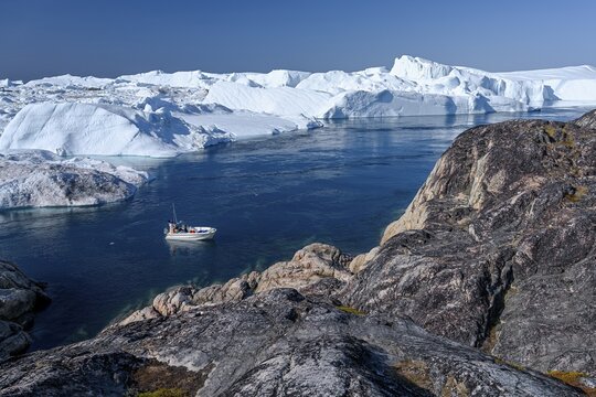 Fishermen with boat in front of gigantic icebergs, UNESCO World Natural Heritage, Ilulissat, Disko Bay, West Greenland, Greenland