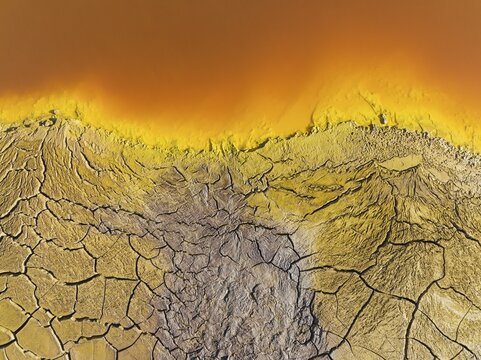 Cracked earth at the bank of the Rio Tinto (Red river) with its deep reddish hue due to oxidised iron minerals in its water, aerial view, drone shot, Huelva province, Andalusia, Spain