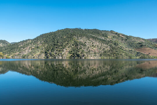 Simetria perfeita entre o Rio Tua e as encostas, um espelho de &aacute;gua sereno sob o c&eacute;u azul profundo de Tr&aacute;s-os-Montes em Portugal