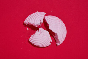 Fototapeta premium A piece of broken marshmallow on a red stylish background. Marshmallows with filling