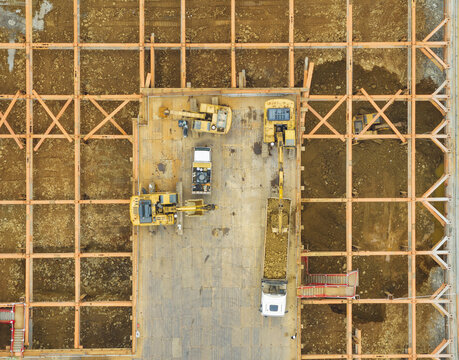 Aerial view of building foundation engineering with excavators and heavy machinery working within a large orange steel grid framework on a construction site Taiwan.