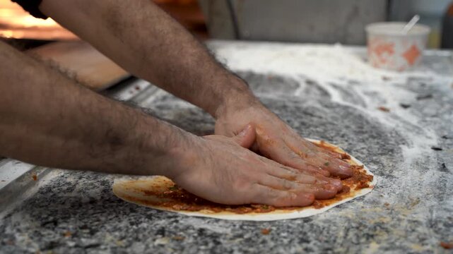 Chef making Turkish pizza lahmacun in bakery kitchen